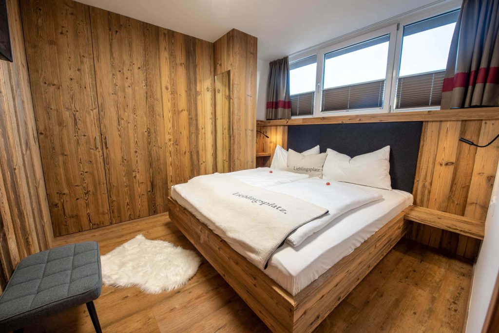 Gemütliches Schlafzimmer mit Holzverkleidung und modernem Doppelbett in Königsleiten.